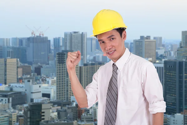 Happy engineer with arm raised, concept of successful, city back