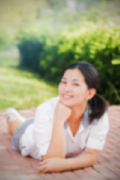 Blur effect of young asian woman relaxing outdoors looking happy and smiling