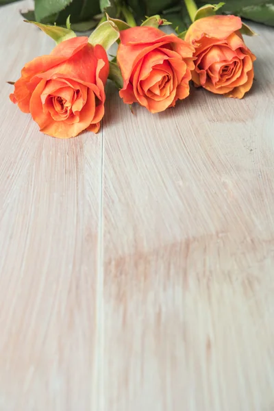 A bouquet of orange roses on wooden table. Copy space