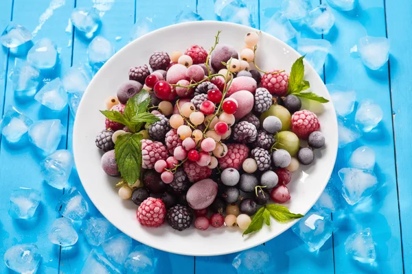 Frozen berry on blue background (currants, raspberries, blueberr