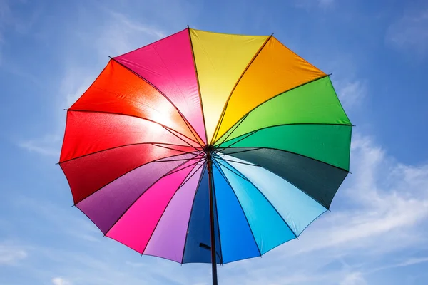Open colorful rainbow umbrella on blue sky background