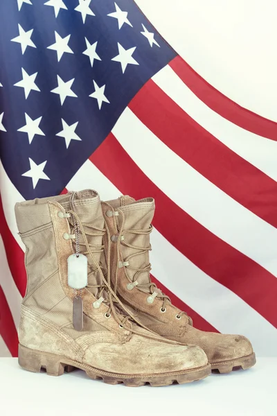 Old combat boots and dog tags with American flag