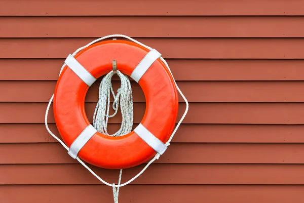 Ring buoy on red wooden wall, copy space