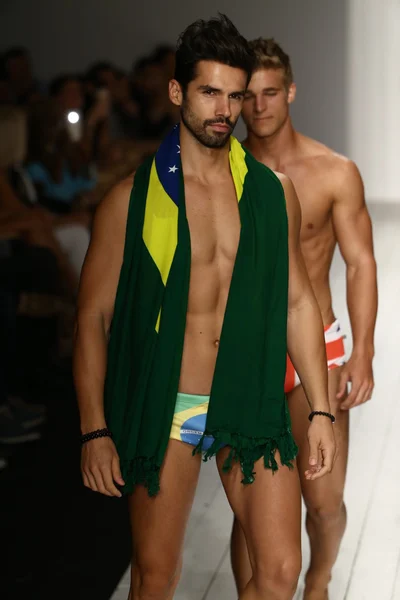 Models walks runway in designer swim apparel