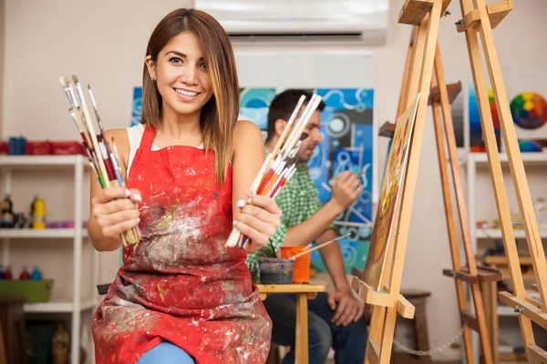 Brunette  holding a bunch of paintbrushes