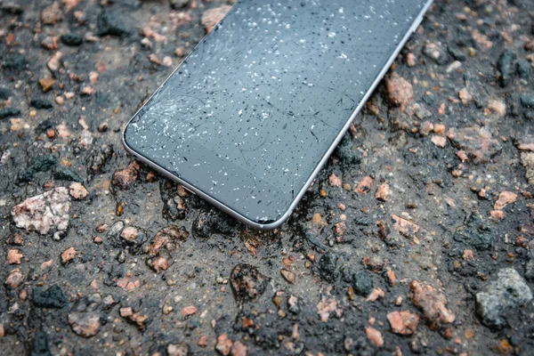 Phone with broken screen on asphalt