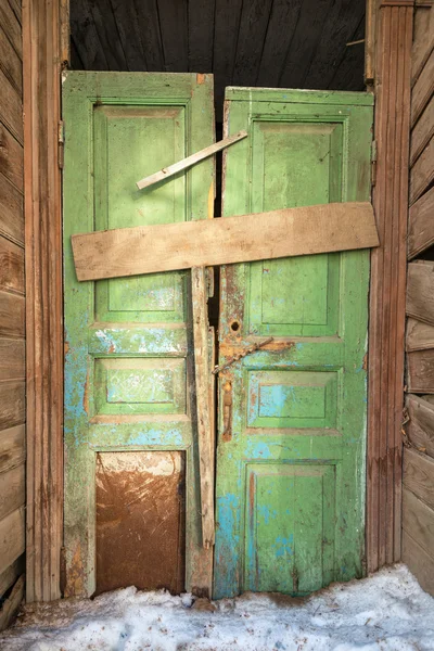 Crooked green door in old wooden house.