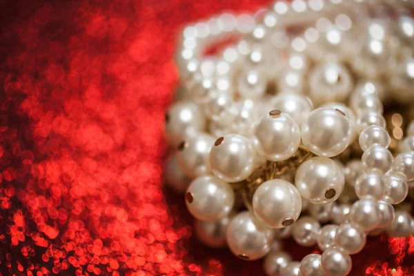 Jewelry background with white pearls on a red glitter