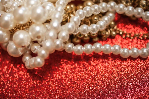 Jewelry background with white pearls on a red glitter
