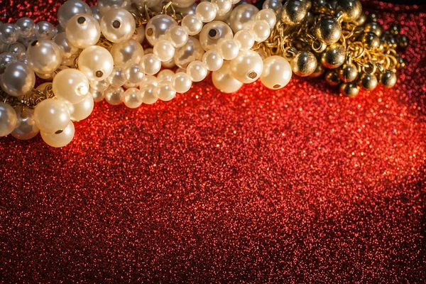 Close up of white pearls on a red glitter background.