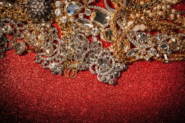 Golden and silver jewelry on red shiny glitter background