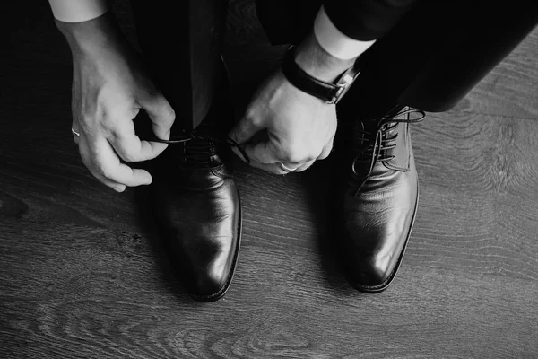 Business man dressing up with classic, elegant shoes. Groom wearing shoes on wedding day, tying the laces and preparing.