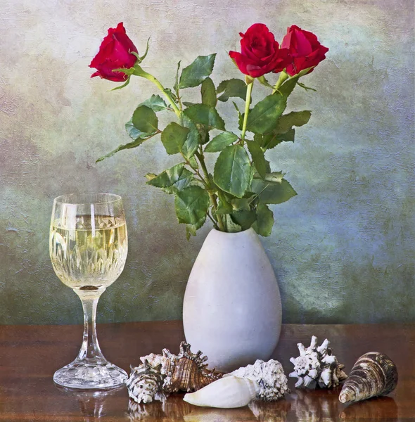 Red roses in vase, white wine glass and shells