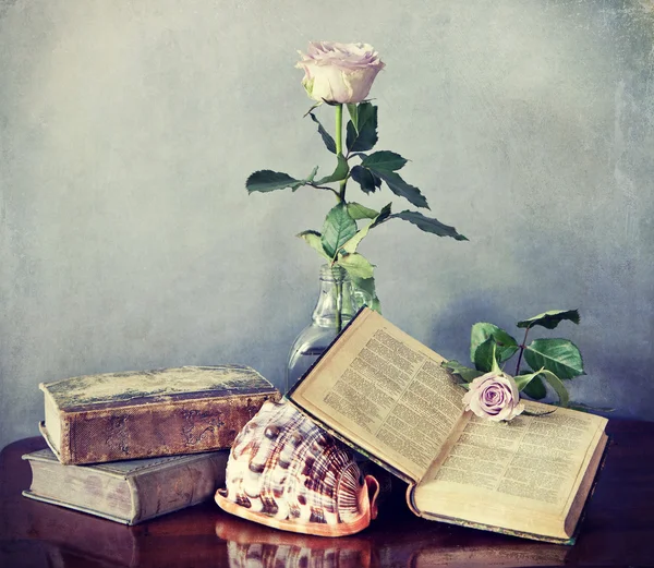 Antique books, shell and  pink rose in glass