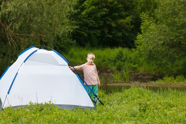 Cute small boy fishing on the river. Camping on the bank of river