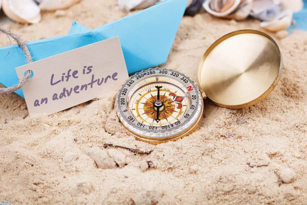 Compass in the sand with sign - Life is an adventure