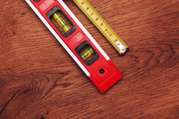 Tape measure and building level on wooden background