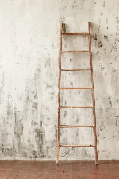 A wooden staircase in an empty room on the background of a concrete wall