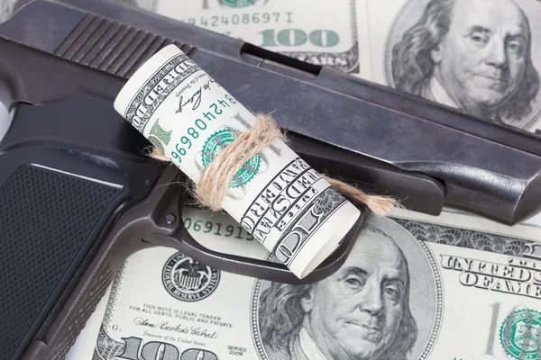 Black gun is lying on dollar bills
