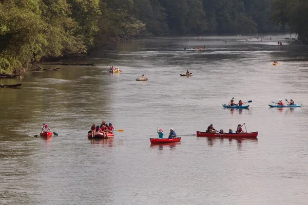 People Raft And Canoe Down River On Hot Summer Day