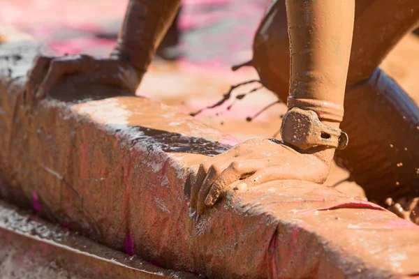 Closeup Female Muddy Hands Grabbing Barrier At Mud Run Event