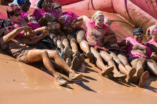 Group Of Muddy Women Hold Hands Sliding Into Mud Pit