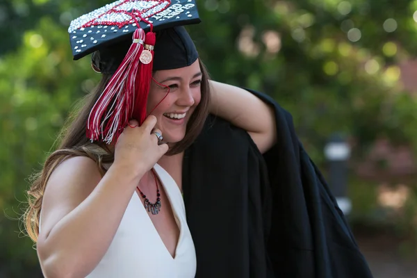 Smiling Female College Graduate Prepares To Put On Graduation Robe