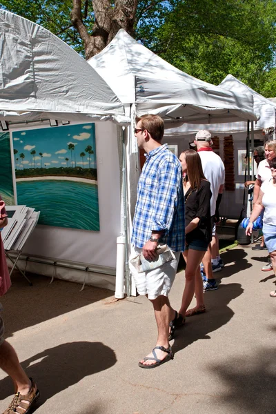 Young Couple Looks At Paintings On Display In Arts Festival