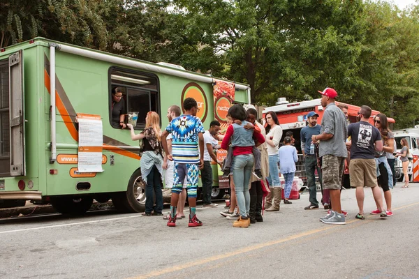 Customers Stand In Line To Buy Meals From Food Trucks