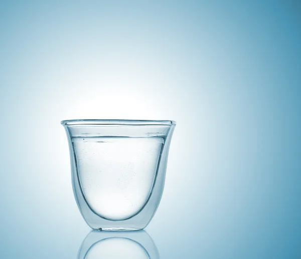 Glass with carbonated water on blue gradient background