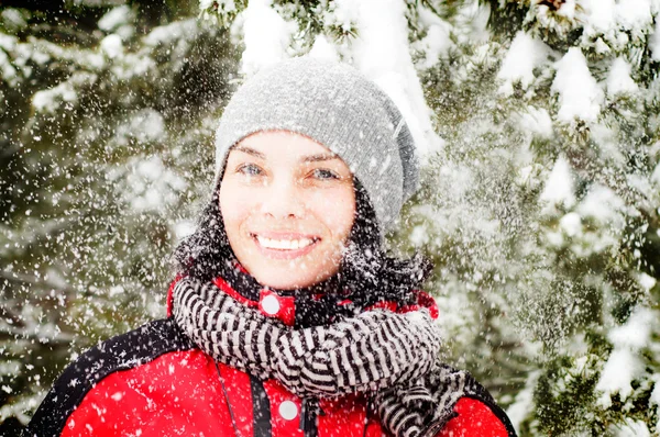 Beautiful winter portrait of young woman with snow falling on her face in the winter snowy scenery
