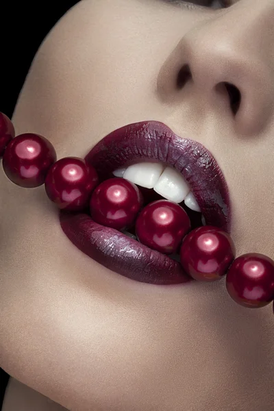 Woman bitting with red lips red pearls