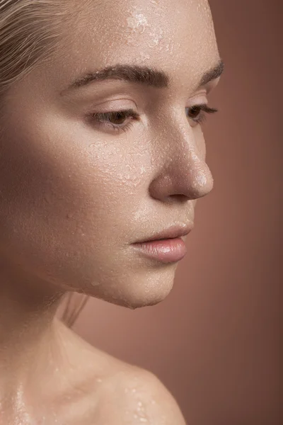 Portrait of woman with wet face on brown background