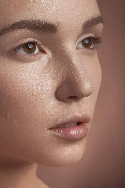 Portrait of woman with wet face on brown background