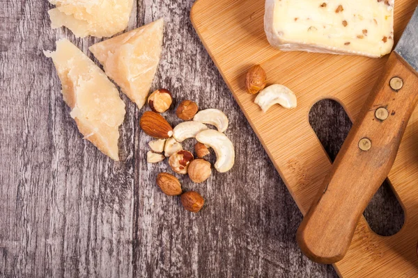 Different type of cheese and nuts on wooden background