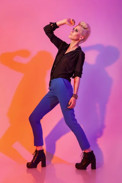 Woman with stylinsh haircut posing on pink background with color