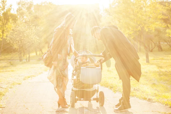 Happy familly with their kid in the park. Image with sun rays ab