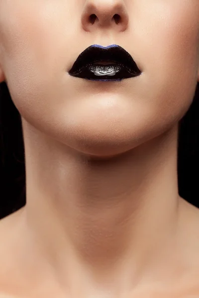 Lips with black lipstick and a blue line in conceptual make up
