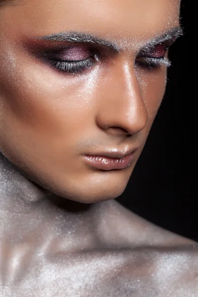 Man in creative make up with glitter and eyelashes
