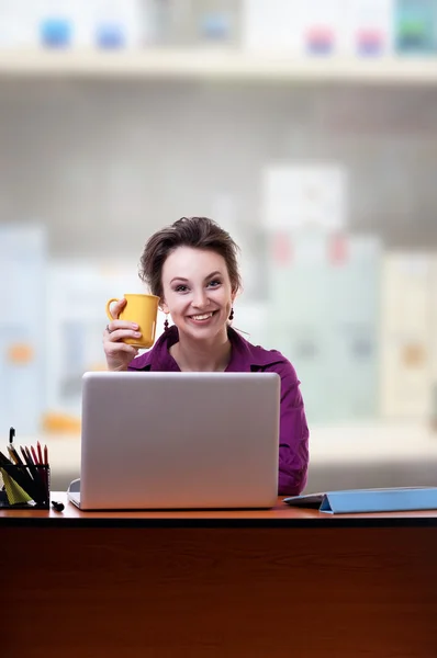 Young businesswoman at an office desk with a cup of coffe