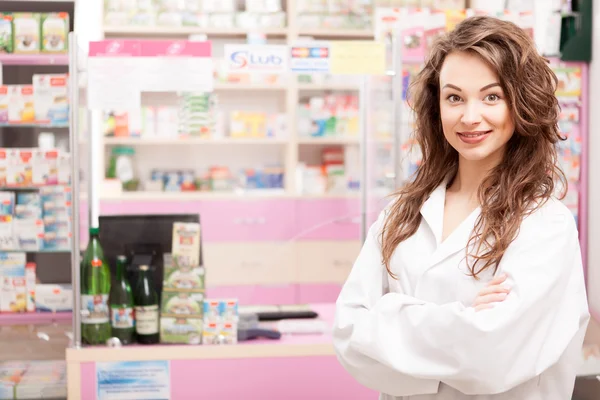 Smiling pharmacist in uniforme in front of the desk