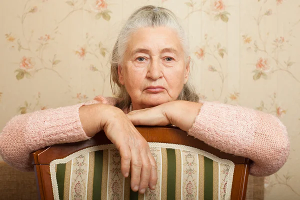 Elderly woman grieves at home.