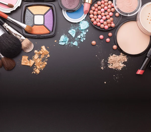 Various makeup products on dark black background with copyspace