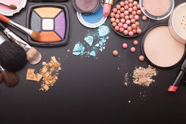 Various makeup products on dark black background with copyspace