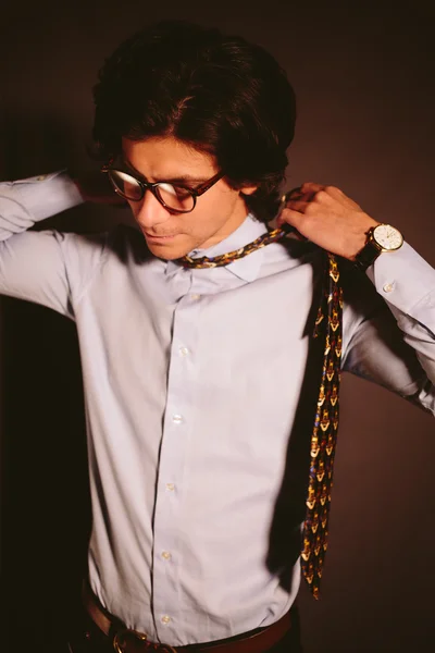 Young man businessman with glasses takes off a tie.