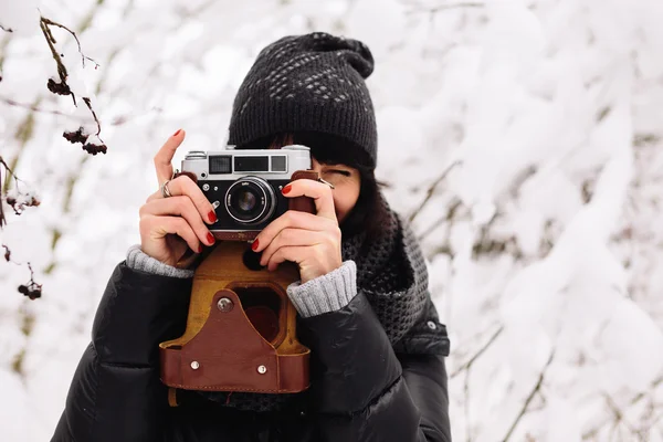 Smiling girl photographed on a camera in winter forest