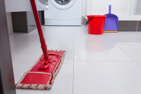 Colorful red mop on a white tiled floor