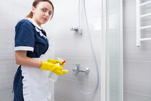 Housekeeper cleaning the inside of a shower