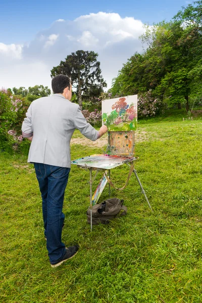 Lonely male artist working outdoors in the park or garden