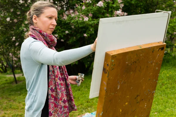 Serious professinal female artist painting a masterpiece outdoor